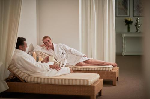 
a woman sitting on a bed next to a man at Fonteverde Lifestyle & Thermal Retreat - The Leading Hotels of the World in San Casciano dei Bagni
