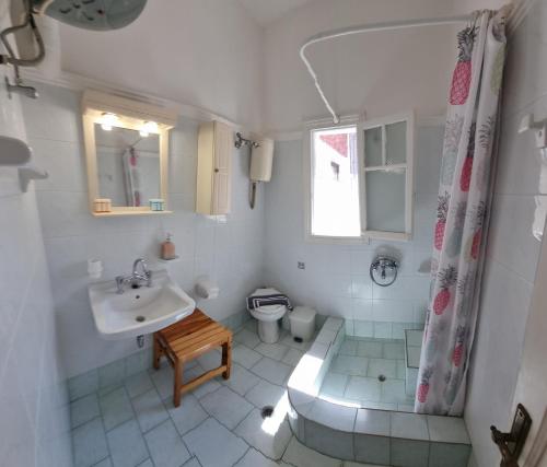a white bathroom with a sink and a toilet at Anemona Apartments and Studios in Vasilikos