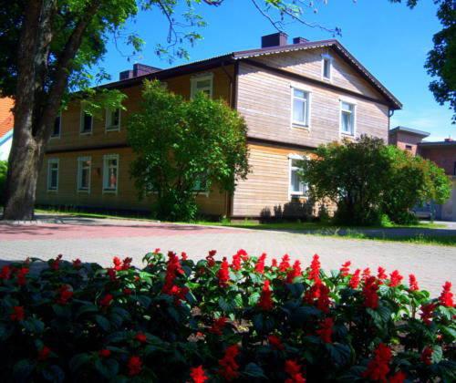 a house with a bunch of red flowers in front of it at Isabela Apartments in Palanga