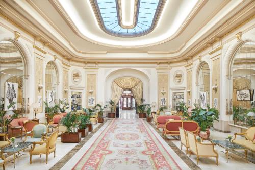 eine Lobby mit Stühlen, Tischen und einer Decke in der Unterkunft Hotel El Palace Barcelona in Barcelona