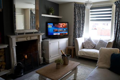 Stunning 5 Bedroom Victorian home with optional hot tub في برشور: غرفة معيشة فيها موقد وتلفزيون