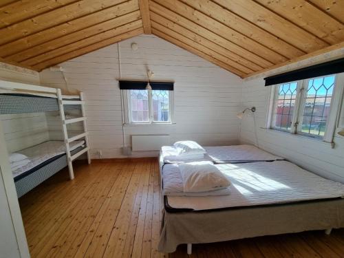 a room with two bunk beds and two windows at Talluddens Stugby in Färjestaden