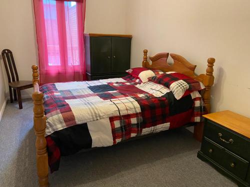 a bedroom with a bed with a plaid quilt at Gestion clin d Oeil 349 in La Tuque