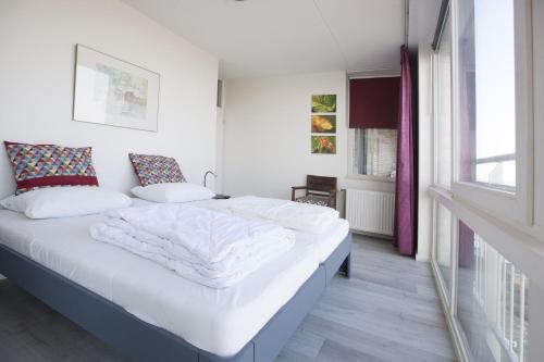 sypialnia z łóżkiem z białą pościelą i oknem w obiekcie Kustverhuur, Appartement aan zee, Port Scaldis 05042 w mieście Breskens