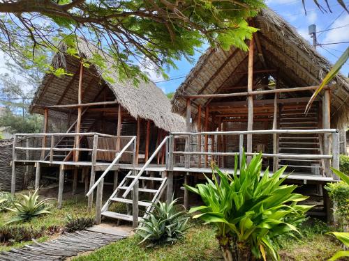 a house with a thatched roof and stairs in front of it at Casa Surf Lodge - Tofo in Praia do Tofo