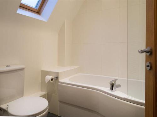 a bathroom with a toilet and a tub and a sink at Bakery Cottage - Lake District in Bowness-on-Windermere