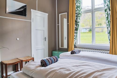 two beds in a room with a window at Hafaldan HI hostel, old hospital building in Seyðisfjörður