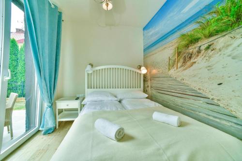 1 dormitorio con 1 cama y una pintura de playa en Holiday resort, Grzybowo en Grzybowo