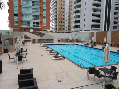 a large swimming pool with chairs and umbrellas at Flat no la residence com acesso a clube in Vitória