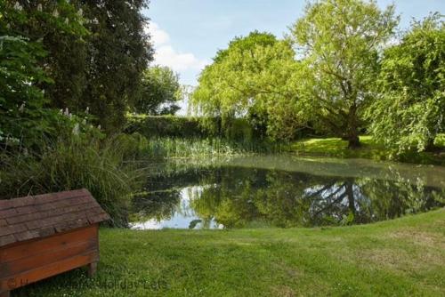 a pond in a park with a bench next to it at The Stables , Birdham in Birdham