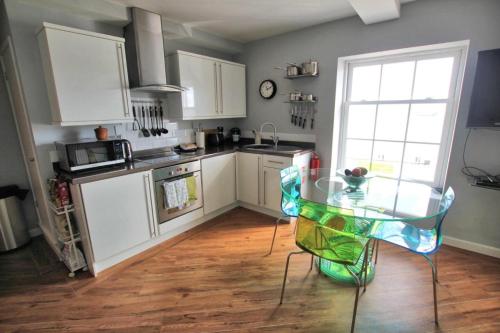 a kitchen with a glass table and a window at Headland View. Luxury. Harbour-Front. With Parking in Falmouth