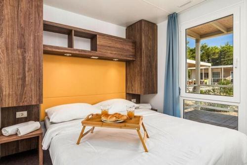 a bedroom with two beds and a tray of food on a table at Mobile Home Pag near Pebble Beach & Pools in Novalja
