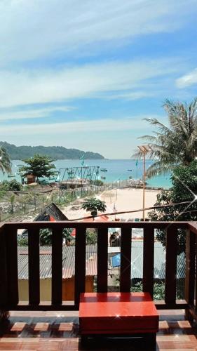 a red bench sitting on a balcony overlooking a beach at Perhentian Hazipah in Perhentian Island