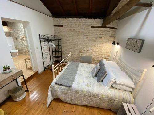 a bedroom with a bed and a brick wall at Le Figuier - 4 bedroom Farmhouse Gite in Limalonges