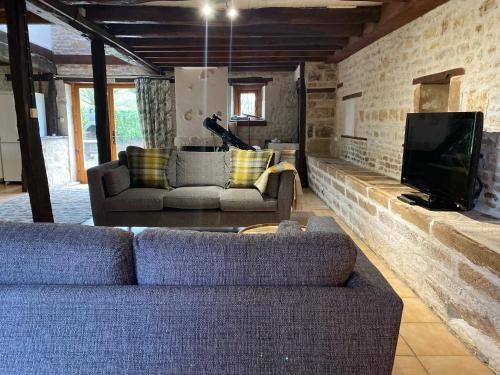 a living room with a couch and a tv at Le Figuier - 4 bedroom Farmhouse Gite in Limalonges