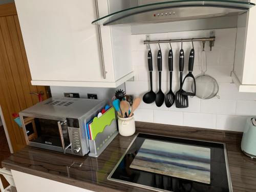 a kitchen with a counter with a microwave and utensils at Headland View. Luxury. Harbour-Front. With Parking in Falmouth