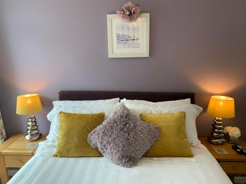a bed with yellow pillows and two lamps on tables at Headland View. Luxury. Harbour-Front. With Parking in Falmouth