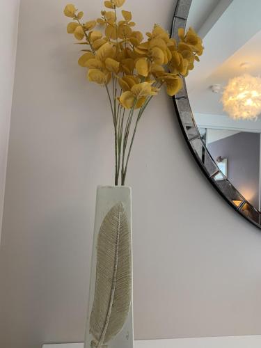 a vase with yellow flowers in front of a mirror at Headland View. Luxury. Harbour-Front. With Parking in Falmouth