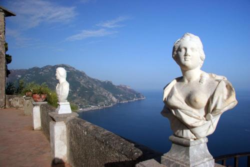 two statues sitting on a wall overlooking the water at Residence Le Villette in Ravello