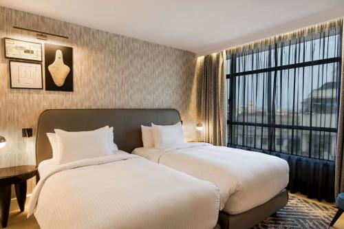 two beds in a hotel room with a large window at Radisson Blu Hotel Casablanca City Center in Casablanca