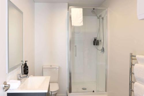 a white bathroom with a shower and a toilet at Ramada by Wyndham Wellington Taranaki Street in Wellington