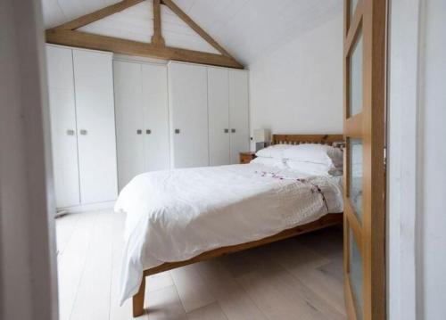 a white bedroom with a bed and white cabinets at Little Barn at Coppice Barn, Birdham in Birdham