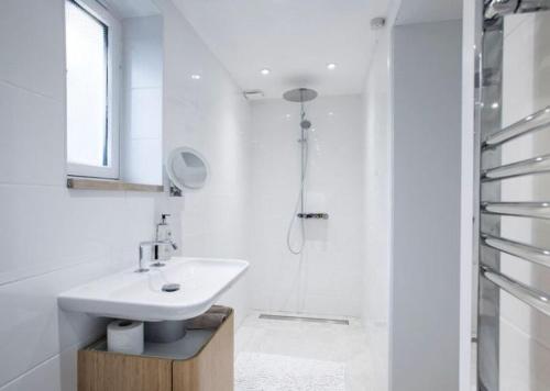 a white bathroom with a sink and a shower at Little Barn at Coppice Barn, Birdham in Birdham
