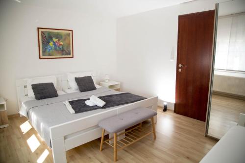 a white bedroom with a bed and a chair at Apartmani Baotić Županja in Županja