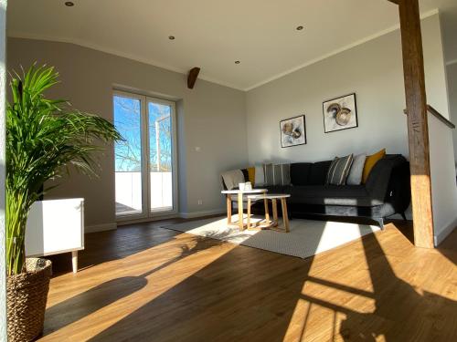 ein Wohnzimmer mit einem schwarzen Sofa und einem Tisch in der Unterkunft Ferienwohnung Watt'n Ausblick in Simonsberg