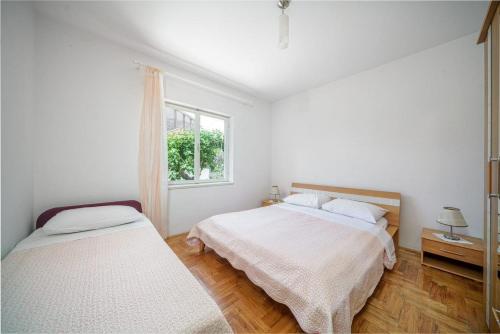 een witte slaapkamer met 2 bedden en een raam bij Apartment Plava Beach in Vodice