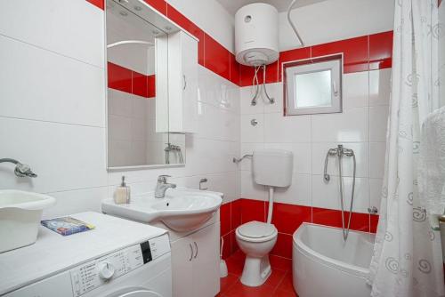 een rood-witte badkamer met een wastafel en een toilet bij Apartment Plava Beach in Vodice