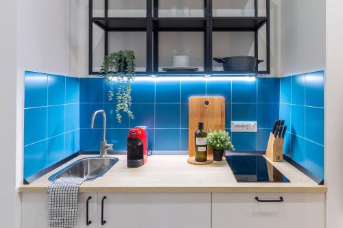 a blue tiled kitchen with a sink and a bottle of wine at Cool and stylish city apartment - WiFi in Trieste