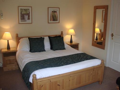 a bedroom with a bed with two lamps and a mirror at The Fox Inn in Matching