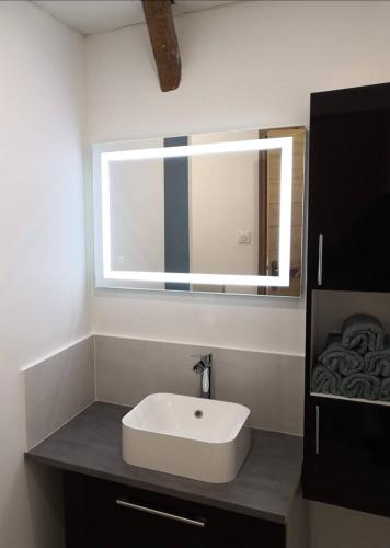 une salle de bain avec un lavabo blanc et un miroir dans l'établissement Le Temps Suspendu, à Saint-Pierreville