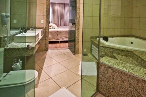 two pictures of a bathroom with a tub and a bedroom at Hotel Canoeiros in Pirapora