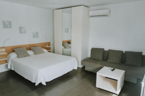 1 dormitorio con cama blanca y sofá en Apartamentos ZHR 2, en Zahara de los Atunes