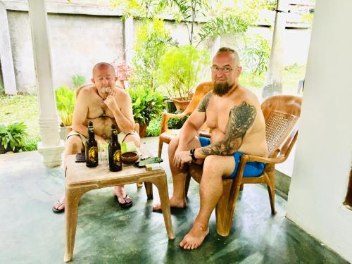 two men sitting in rocking chairs with beer bottles at Bindu Homestay in Wellawaya