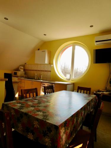 a kitchen with a table with chairs and a window at Csetáj Vendégház in Hajós