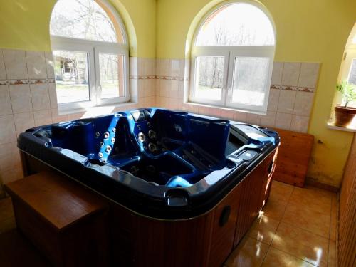 eine große blaue Badewanne im Bad mit zwei Fenstern in der Unterkunft Csetáj Vendégház in Hajós