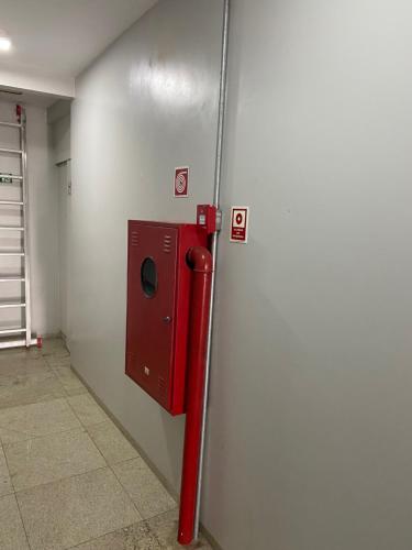 a metal wall with a red dispenser in a room at Hotel Vitrine in Goiânia