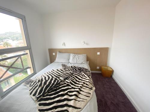 - un lit à motifs zébrés dans une chambre avec fenêtre dans l'établissement à 10 min de la Croisette - pieds dans la mer, à Cannes