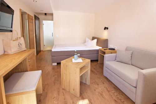 a living room with a bed and a couch at Hotel Hirsch in Oberstaufen