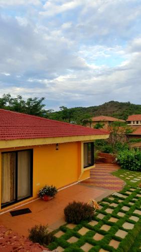a yellow house with a red roof and a yard at Redstone Hills, Diveagar in Diveagar