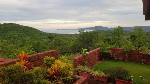 a garden with a brick wall and some plants at Redstone Hills, Diveagar in Diveagar