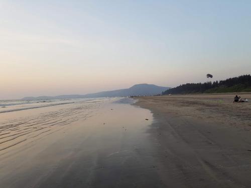 a beach with a person flying a kite at Redstone Hills, Diveagar in Diveagar