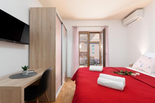 una camera con letto rosso, scrivania e TV di Villa Marko Kaštelir a Kaštelir (Castellier)