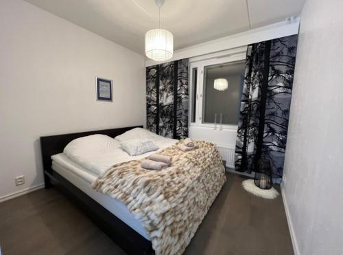 ein Schlafzimmer mit einem Bett mit einer Decke und einem Fenster in der Unterkunft Spacious City Center Apt - Sauna - Self Check in in Rovaniemi
