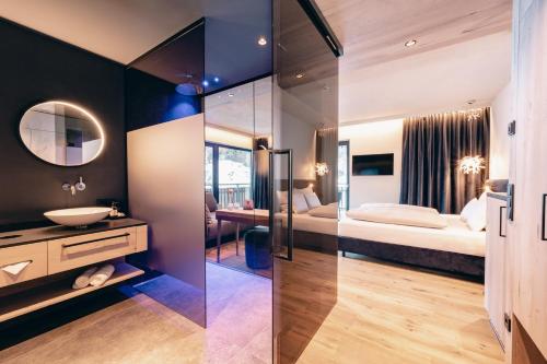 a bathroom with a bed and a sink and a mirror at ZillergrundRock Luxury Mountain Resort in Mayrhofen
