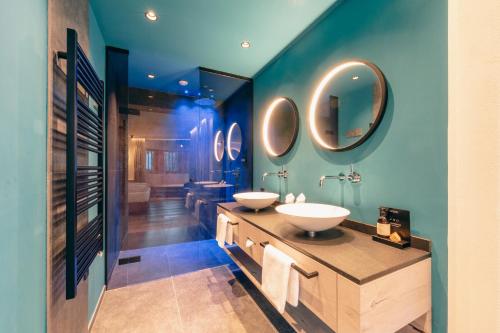 a bathroom with two sinks and a large mirror at ZillergrundRock Luxury Mountain Resort in Mayrhofen