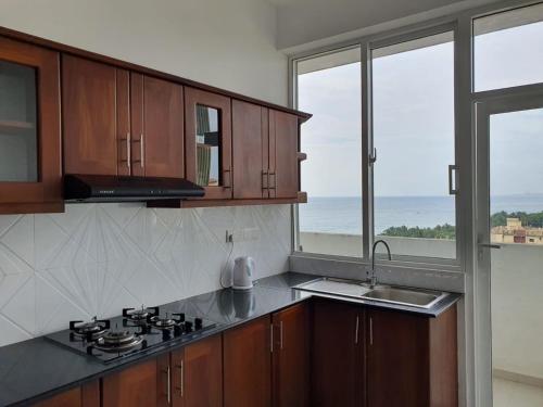 a kitchen with a stove and a sink and windows at New 2 bedroom apartment, 100m away from the beach in Dehiwala